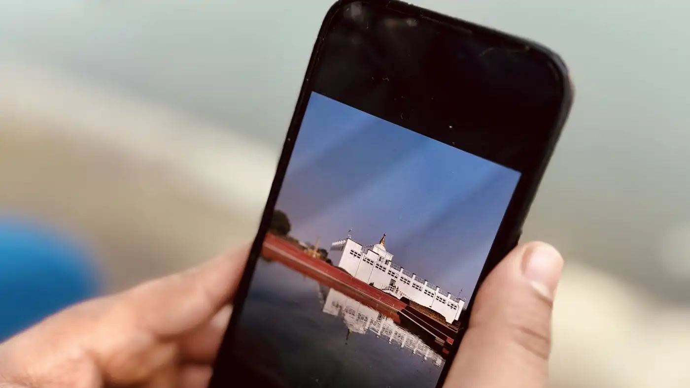 Two hands holding a smartphone over a blurred lakeside background