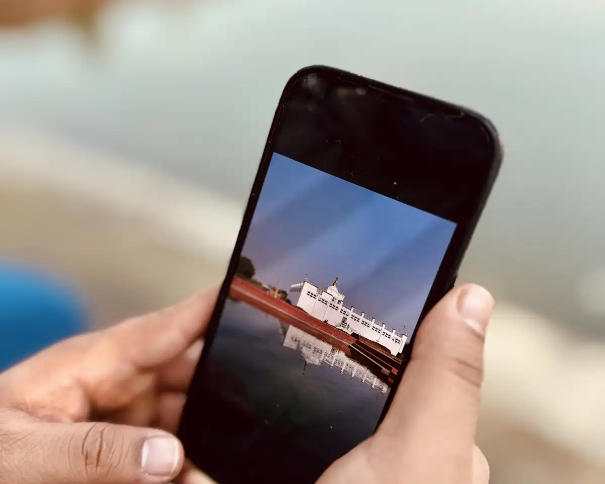 Two hands holding a smartphone over a blurred lakeside background