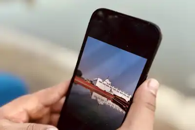 Two hands holding a smartphone over a blurred lakeside background